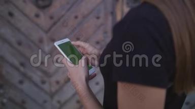 一个人使用带有触摸绿色屏幕的蜂窝电话浏览社交网络和通信特写。 女孩